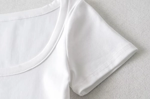 Close-up of white rib-knit short top showing fine texture and clean neckline stitching
