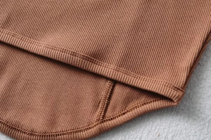 Detail of caramel ribbed fabric showing stitching and curved hem on the slim tank top