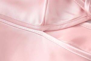 Detail of pink satin fabric showing high-quality stitching and smooth silky texture
