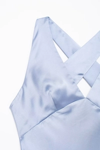 Close-up detail of smooth light blue satin fabric and V-neckline on midi dress