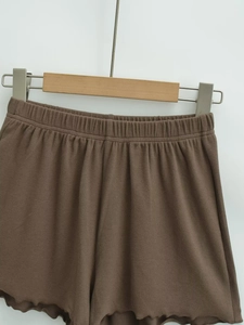 Detail of high-waist brown knit shorts with elastic waistband and wavy lettuce edges