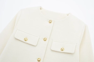 Detailansicht der cremefarbenen Tweedjacke mit Webstruktur und Goldknöpfen