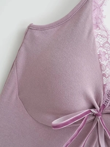 Détail d'une robe en tricot côtelé lilas avec dentelle délicate et nœud en velours