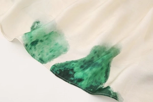 Detail of silk-texture fabric with emerald green ink pattern and fine rolled hem stitching