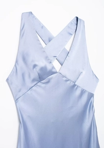 Detail of light blue satin midi dress featuring a criss-cross halter neckline design