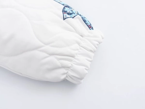Close-up of white quilted jacket cuff with elastic hem and floral patterned sleeve details