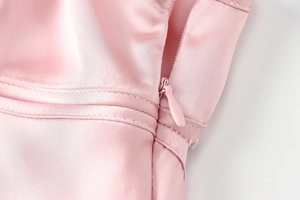 Close-up of invisible zipper detail on pink satin dress showing quality stitching