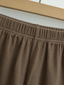 Detail view of elastic waistband on dark brown wide-leg shorts with ribbed texture