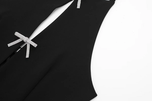 Detailaufnahme des Neckholder-Tops mit Strass-Schleife und Ausschnitt auf schwarzem Stoff