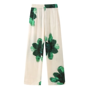 Detail view of elastic high waist and green floral print on cream wide leg pants
