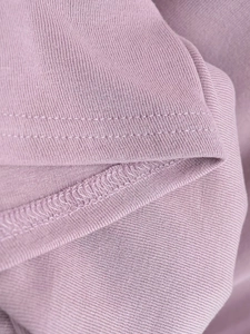 Détail macro de l'ourlet de la robe en tricot violet clair avec coutures de qualité