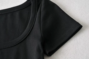 Detailed close-up of double-stitched neckline and hem on a black slim-fit crop top