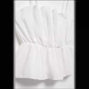 White sleeveless smock camisole with elastic waist and ruffle hem detail