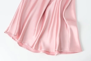 Close-up detail of smooth pink satin dress fabric showing glossy texture and clean stitching
