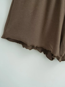 Detail of dark brown ribbed knit fabric featuring elastic wavy lettuce hem finish
