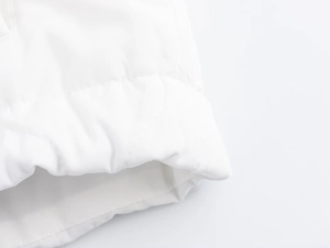 Detailed close-up of horizontal quilting and fabric texture on a white padded jacket hem