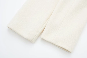 Detaillierte Makroansicht von weißem Tweed-Stoff an den Ärmelbündchen einer Jacke