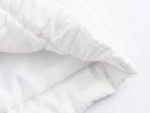 Detail shot of white quilted jacket sleeve showing fine stitching and puffy texture