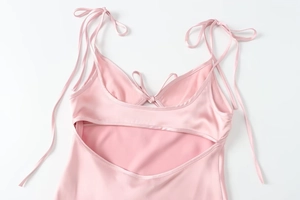 Detail of light pink satin dress featuring adjustable tie straps and a back cutout