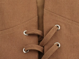 Gros plan du gilet marron texturé avec laçage croisé et œillets métalliques