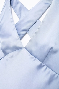 Detail of light blue satin midi dress featuring a sophisticated crossover V-neckline