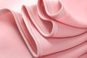 Close-up of pink satin dress fabric showing premium stitching and smooth texture detail