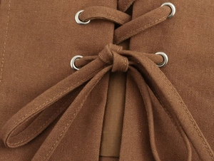 Détail macro du tissu en coton marron avec œillets argentés et design à lacets croisés