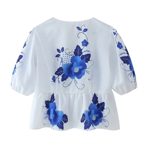 Detail of blue floral print on white puff sleeve blouse with ruffled hem design