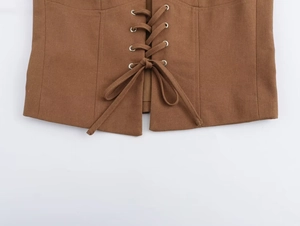 Détail du gilet corset marron avec œillets métalliques argentés et laçage sur le devant