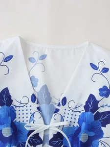 Detailed view of women's V-neck top with white drawstring tie and blue floral pattern