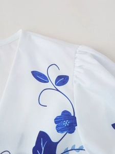 Detailed view of the V-neck and puff sleeves on white top with blue floral print