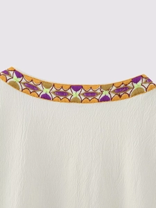 Gros plan du gilet blanc à col rond avec broderies ethniques géométriques colorées