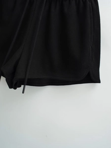 Détail du short en maille côtelée noire avec taille élastique à cordon et fentes latérales