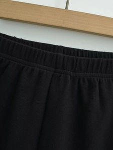 Detail view of high elastic waistband and soft ribbed fabric on black casual shorts