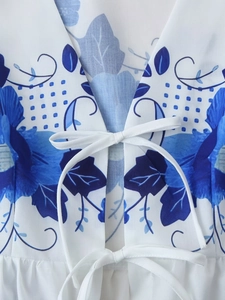 Detail of V-neck with white tie bows and blue floral print on cotton fabric garment