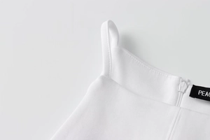 Close-up of white summer dress featuring thin straps, hidden zipper, and high-quality fabric
