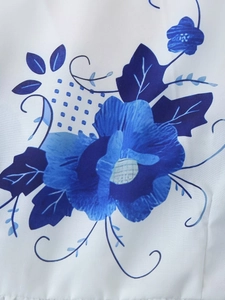 Detailed close-up of vintage blue and white floral porcelain print on white summer blouse fabric