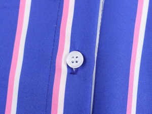 Detailed macro view of vertical striped fabric with a white four-hole button and stitching