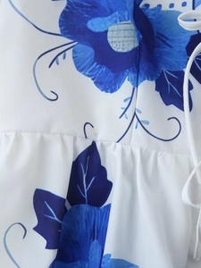 Detailed view of blue floral print on white fabric with waist drawstring and stitching