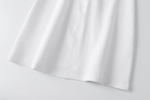 Detail of the white halter dress featuring fine hem stitching and textured fabric