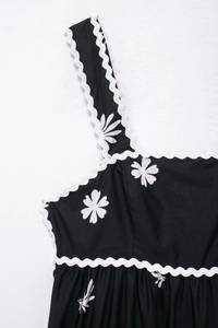 Détail de l'imprimé marguerite blanche sur tissu noir avec élégante bordure en dentelle ric rac