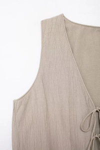 Detailed macro view of beige textured fabric with drawstring ties on a sleeveless top