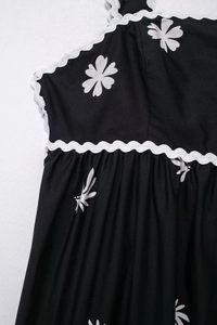 Détail de robe midi noire à imprimé floral avec bordure en dentelle festonnée blanche