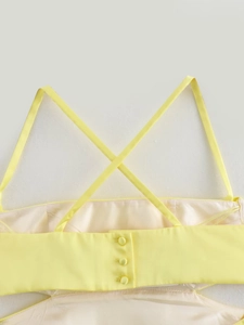 Detail of yellow summer dress with criss-cross straps and fabric-covered buttons on the back