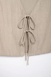 Detailed macro view of the double bow tie-up closure on beige textured fabric