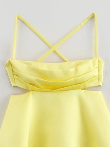Detailed view of yellow satin mini dress featuring cross straps and waist cut-out details