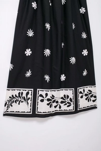 Détail d'une robe mi-longue d'été avec imprimé floral noir et bordure de style vintage