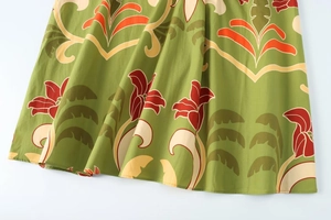 Détail de l'ourlet de robe midi verte avec fleurs rouges et motifs de vignes