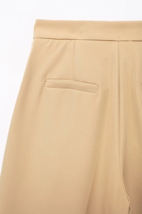 Detailed view of back welt pocket and high waist tailoring on khaki wide leg pants