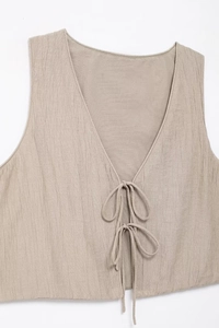 Detail of light brown textured vest top featuring front tie knots and a shallow V-neckline